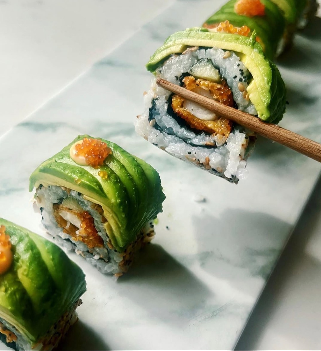 Makis maki recouverts de fines lamelles d'avocat et œufs de poisson